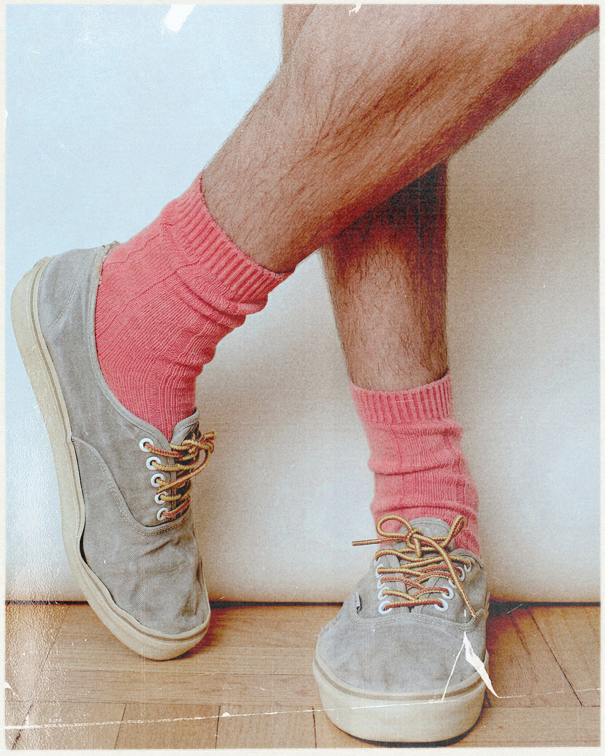 Person wearing pink socks and gray sneakers on a wooden floor.