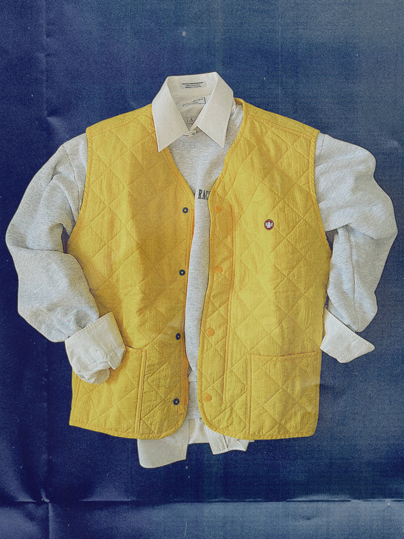 Yellow quilted vest over a white shirt on a blue background