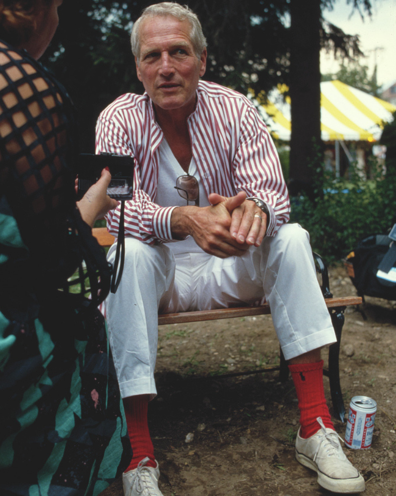 Man sitting on a bench outdoors with a camera and can of beer