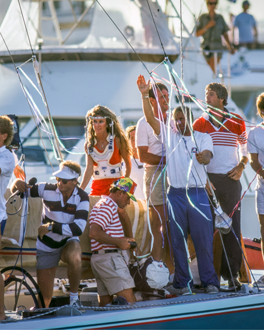 Group of people on a boat with one person raising a fist in victory