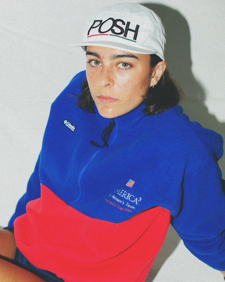 Person wearing a blue and red hoodie  sitting against a plain background.