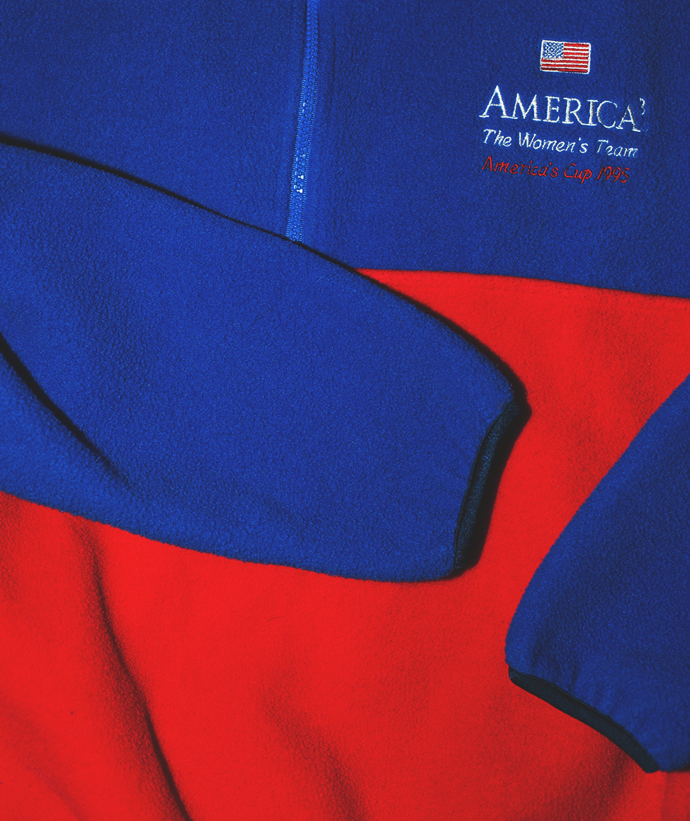 Close-up of a red and blue vintage fleece with 'America's Cup' logo.