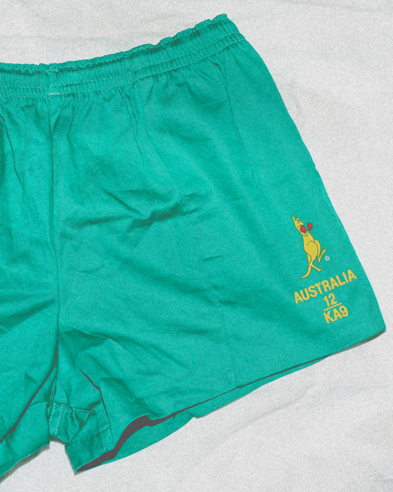 Green shorts with a kangaroo logo on a light gray background
