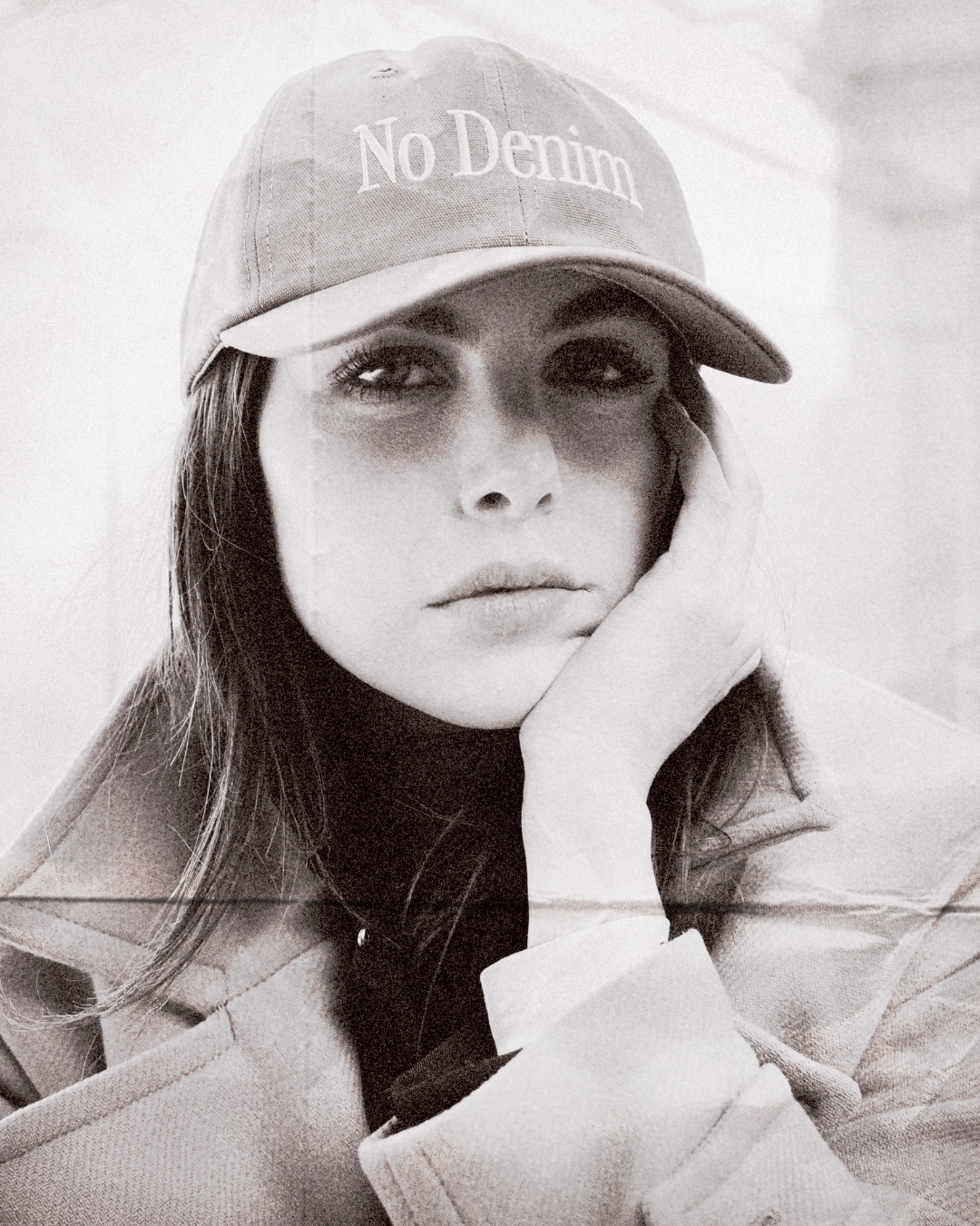 Person wearing a cap with 'No Denim' text in a black and white photo