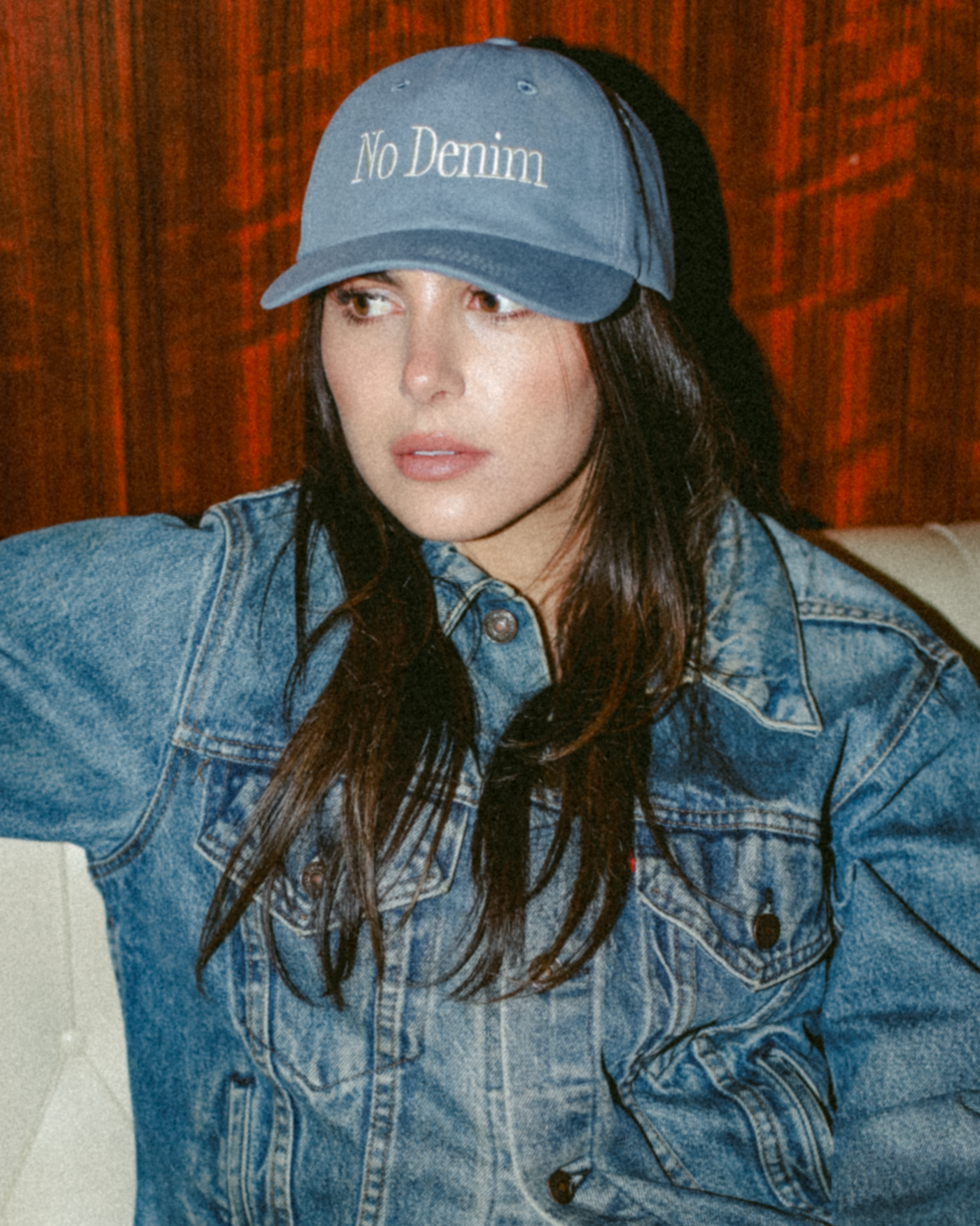 Person wearing a denim jacket and cap with 'No Denim' text against a wooden background