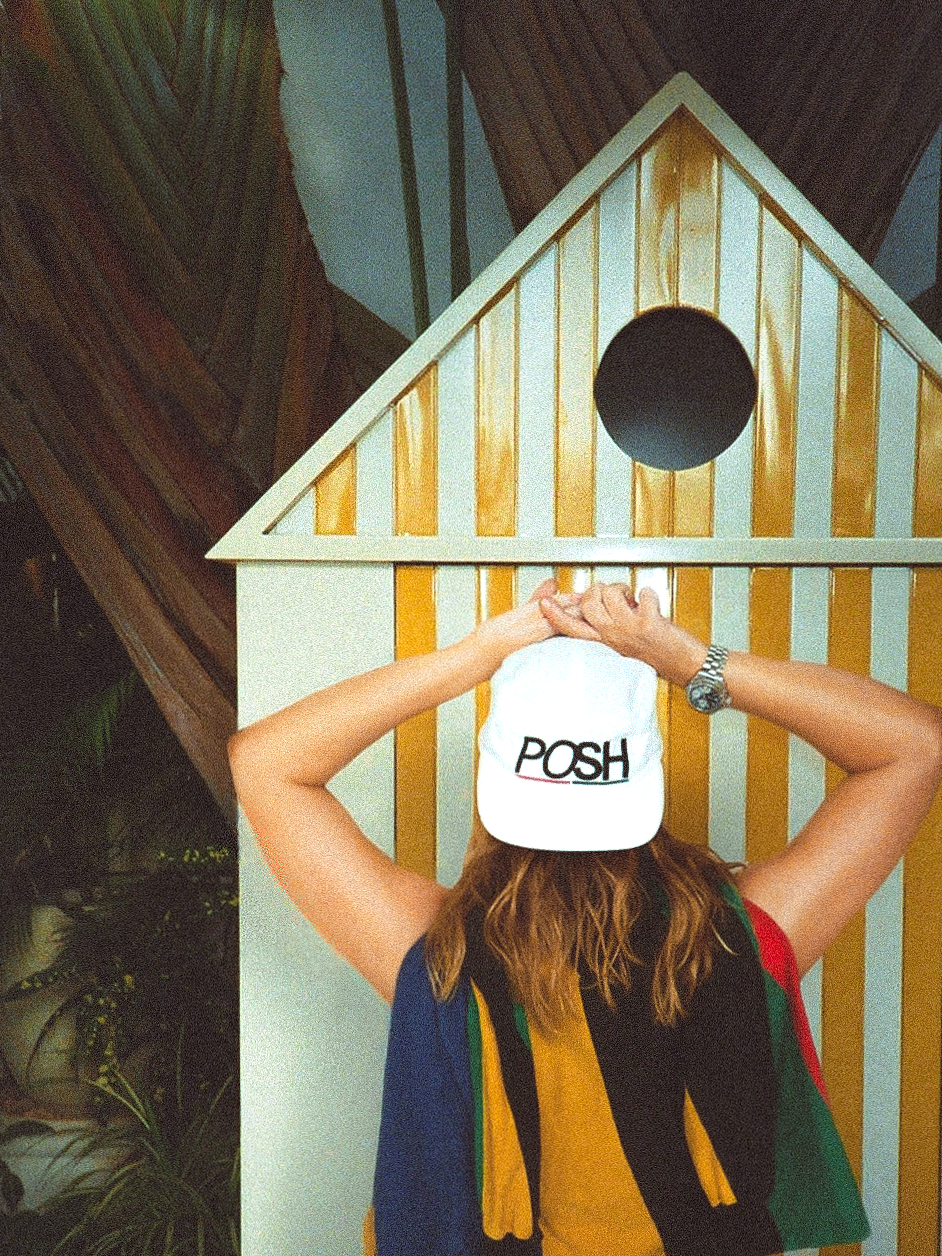 Person wearing a 'POSH' cap with a colorful background