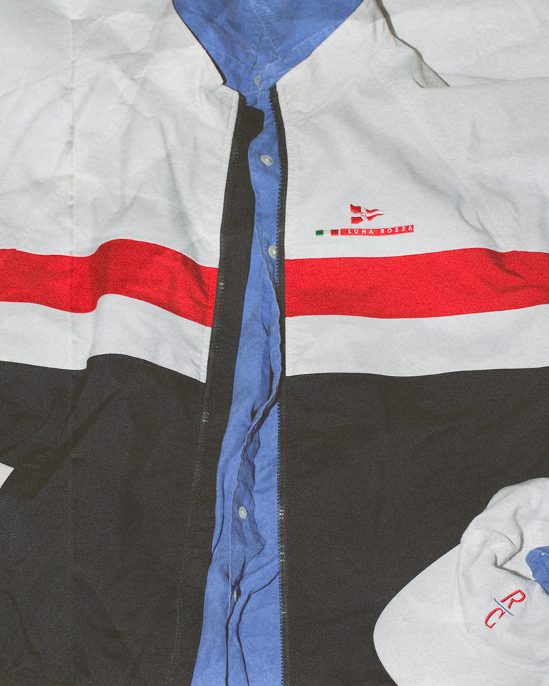 Close-up of a jacket with red, white, and blue stripes and a logo on the chest.