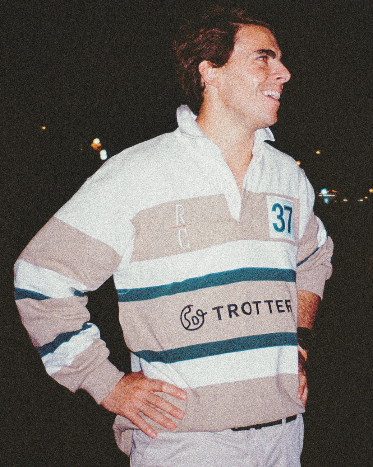 Man wearing a striped sweater with visible branding against a dark background