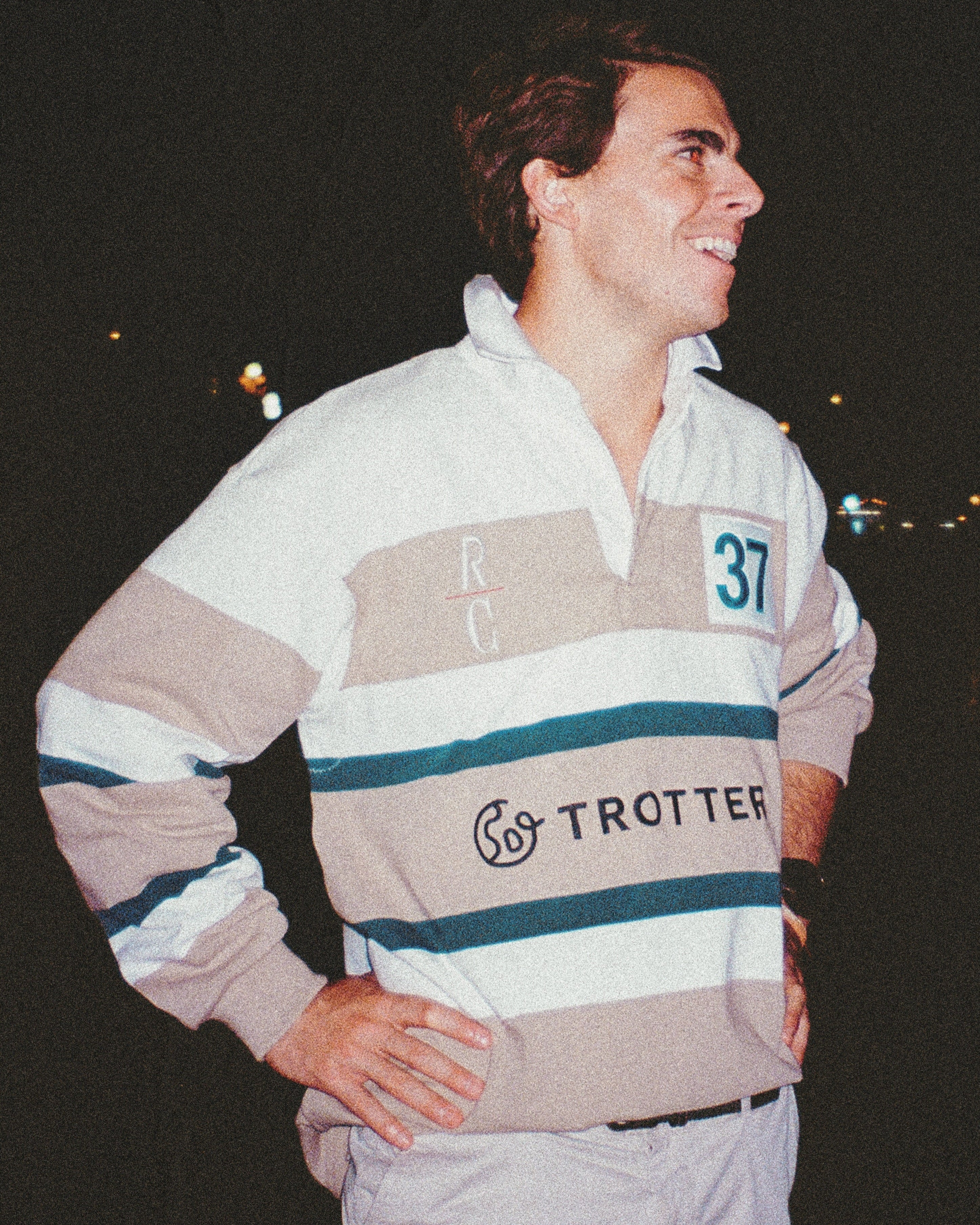 Man wearing a striped sweater with visible branding against a dark background