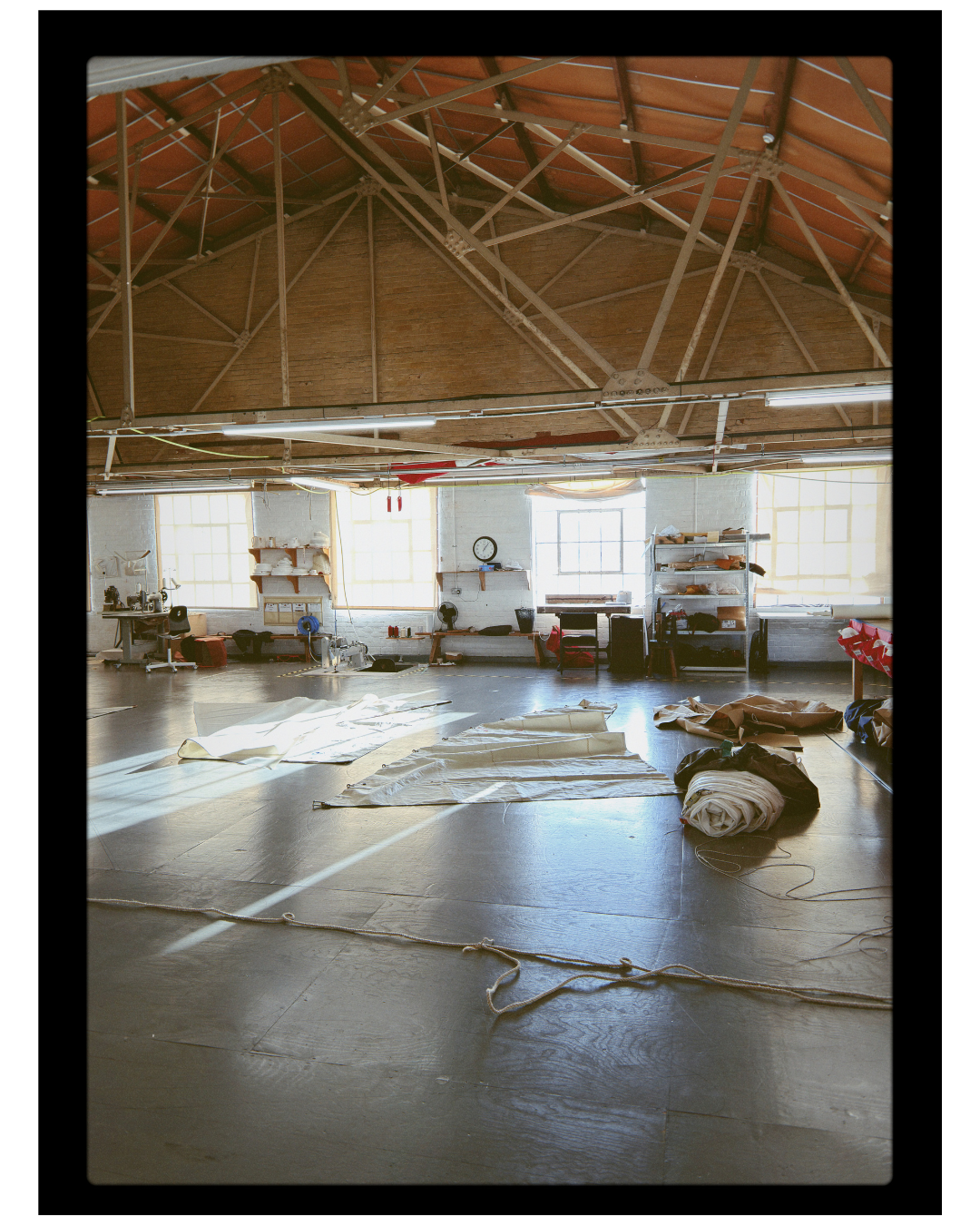 Large warehouse or studio with wooden beams on the ceiling and various items on the floor.