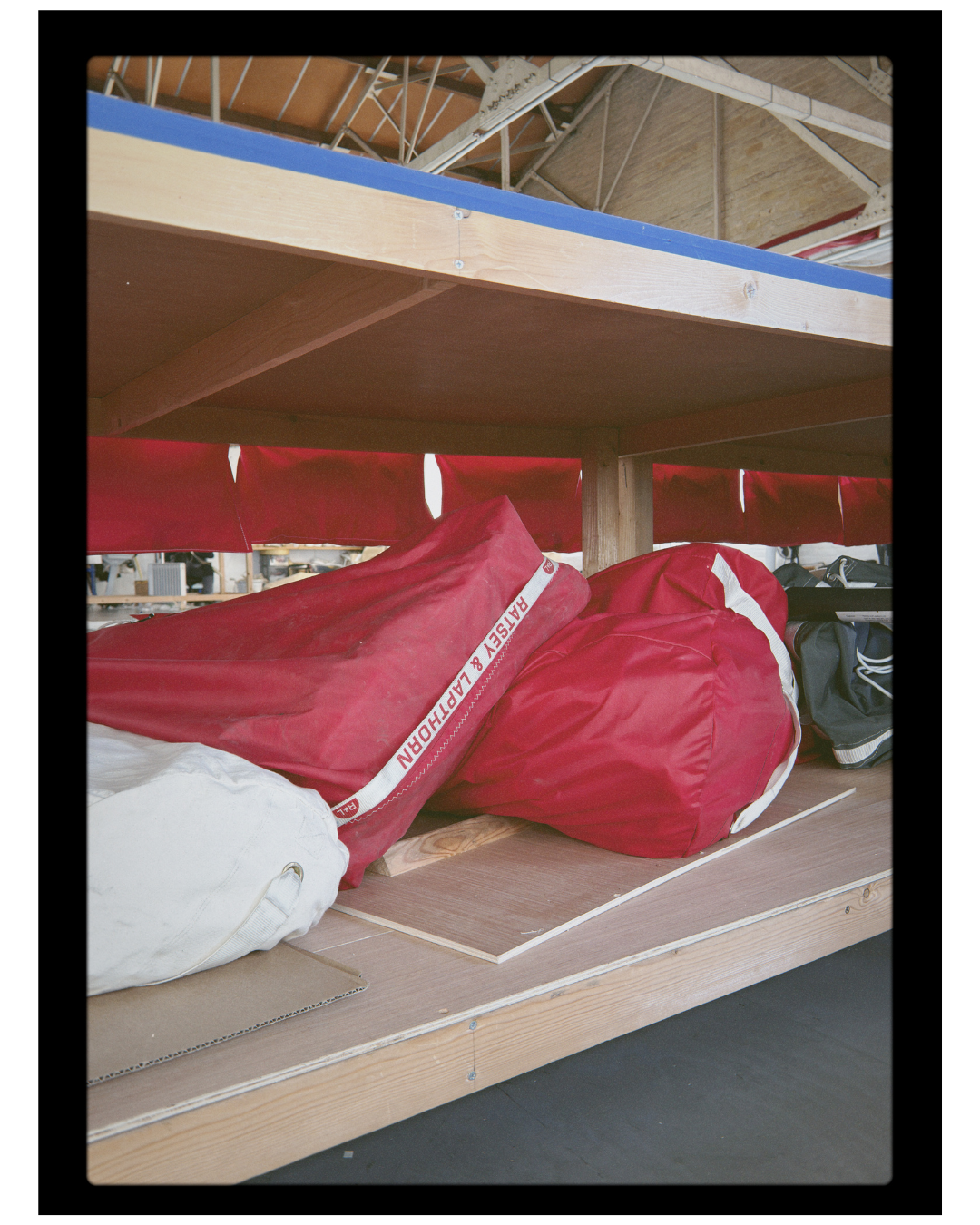 Red sailboats stored inside a warehouse with wooden shelves.